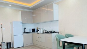 A modern kitchen with light-colored cabinets, a white refrigerator, a microwave, a coffee maker, and a stove. There is a dining table with two chairs. -  205 In the central of Ulaanbaatar, Selbe Comfort Apartment (Ulaanbaatar)