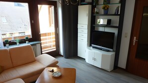 A modern living room with a sofa, a small table, a TV, and a cabinet.