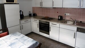 A kitchen with white cabinets, a stove, a sink, and a microwave on the counter.