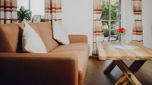 Ein Wohnzimmer mit einer Couch, einem Holztisch und Vorhängen.