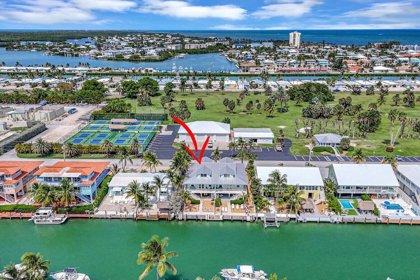 Ein Hotel an der Küste mit einem Jachthafen, Tennisplätzen und einem Pool.