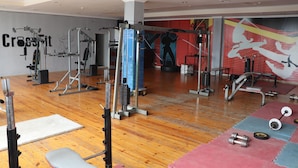 Una palestra con diverse attrezzature per esercizi, pavimento in legno e un muro decorato da un grande murale a tema fitness.