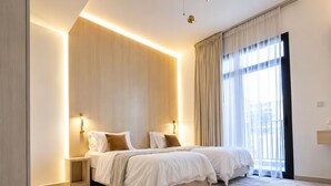 Un dormitorio moderno con dos camas, un ventanal con cortinas y una alfombra de color claro.