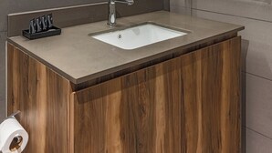Un baño moderno con tocador de madera, un espejo grande y lavamanos empotrado.