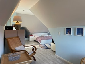 A bedroom with a bed, a chair, a lamp, and a small table.
