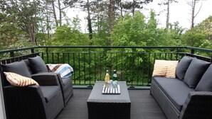 A balcony with two black sofas, a coffee table, and a bottle of orange juice.