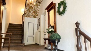 A staircase with a wooden handrail, a wall-mounted light fixture, and a decorative wreath. - House Friesland - Apartment 2 - An urban villa with spacious and tasteful (Sylt)