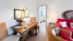 A dining area with a wooden table, chairs, and a red sofa. There are framed pictures on the walls and a lamp on the sofa. - House Friesland - Apartment 3 - An urban villa with spacious and tasteful (Sylt)