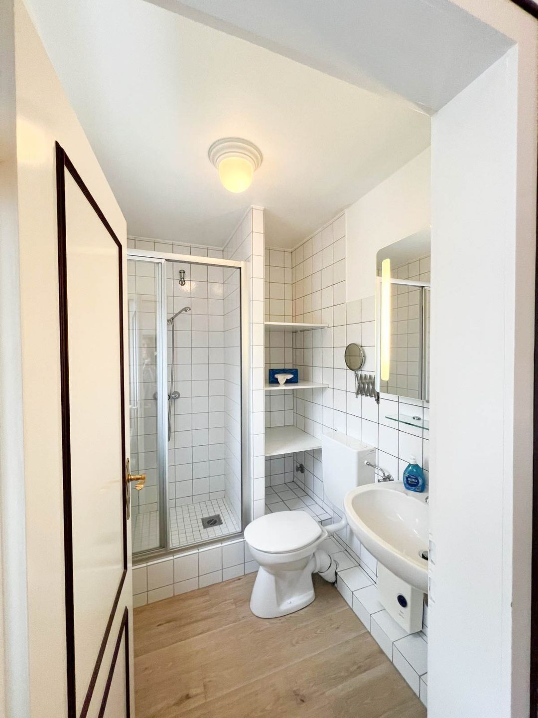 A compact bathroom with a glass-enclosed shower, a toilet, and a sink.