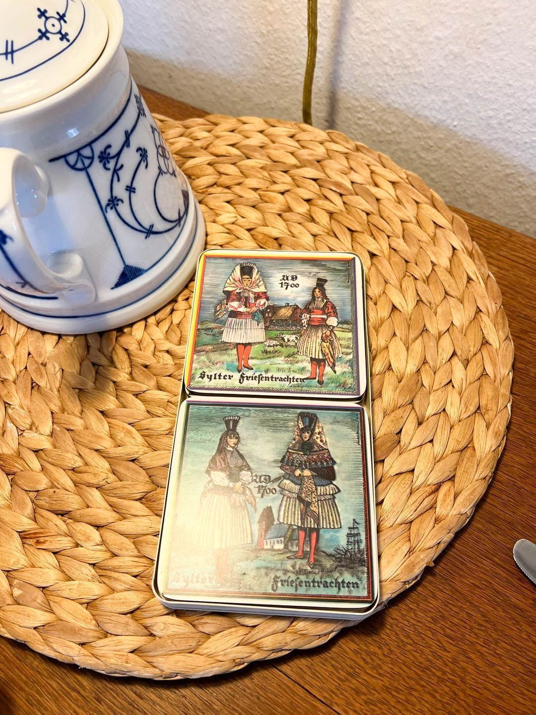 Two playing cards on a woven mat with a ceramic mug in the background.