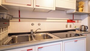 A kitchen with white cabinets, a double sink, and a countertop with a kettle. - Monte Livrio by Interhome (Bormio)