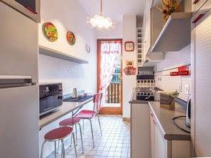 A kitchen with a stove, sink, and chairs.