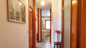 A hallway with a tiled floor, wooden doors, a painting on the wall, and a radiator in the background. - Monte Livrio by Interhome (Bormio)