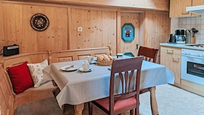 Un acogedor comedor de madera con una mesa dispuesta para dos, una cocina con electrodomésticos modernos y un tragaluz.