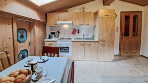 Una cocina acogedora con armarios de madera, una estufa y una mesa de comedor preparada para dos personas.