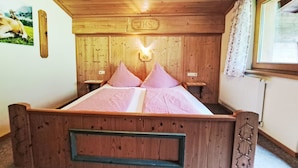 Una cama de madera con ropa de cama a cuadros, un cabecero de madera y una mesita de noche pequeña.