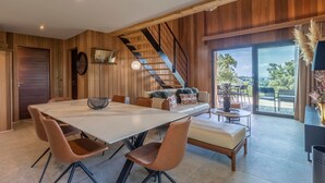 Un intérieur moderne comprenant un coin repas, un canapé, un escalier et un balcon avec vue.