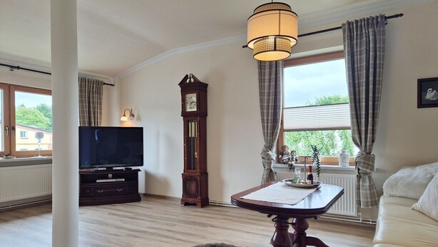 Un salon comprenant un téléviseur, une grande horloge en bois, une table avec un plateau et un canapé.