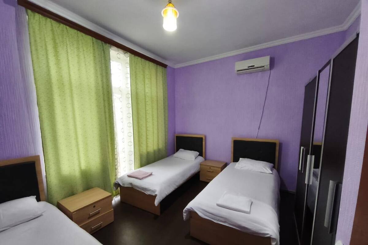 A hotel room with two single beds, a wooden nightstand, a wardrobe, and an air conditioning unit.