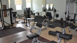 A gym with various exercise equipment, including benches, weight machines, and free weights.