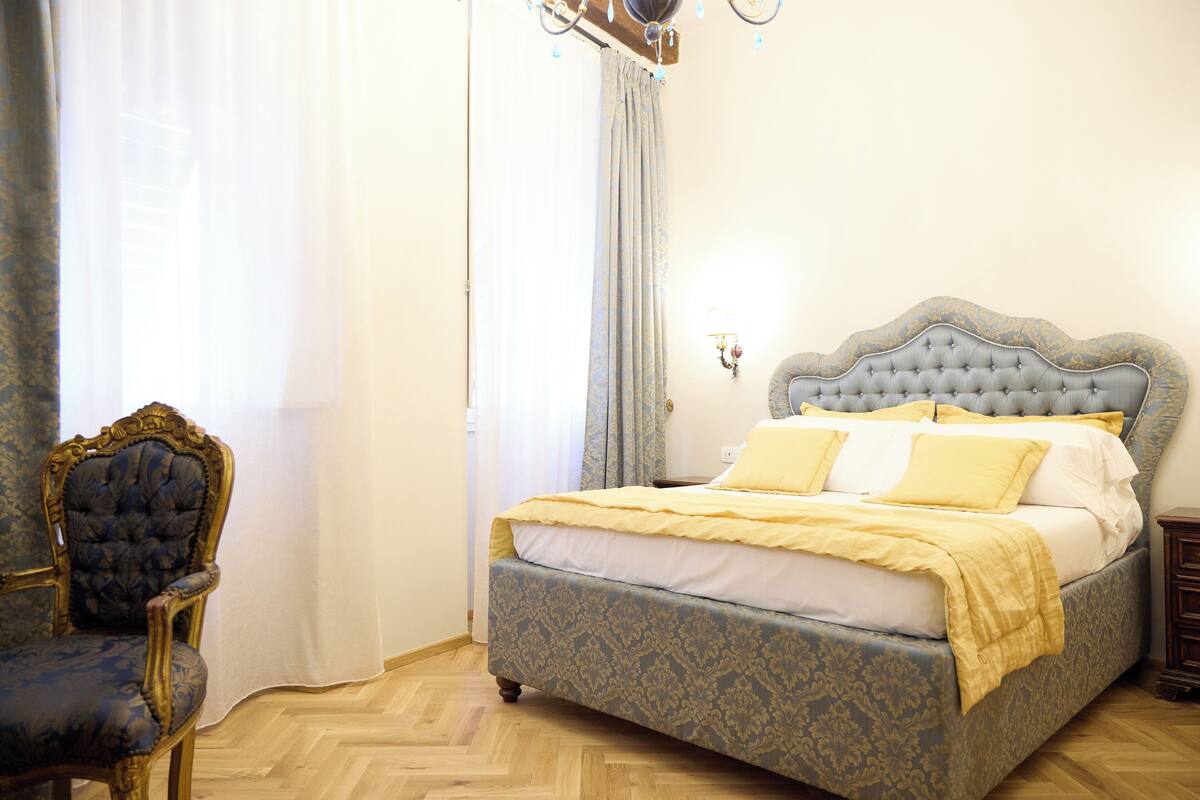 Une chambre à coucher avec un grand lit, une chaise et un lustre.
