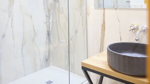 Une salle de bain moderne avec une douche en verre, un mur en marbre, un meuble-lavabo en bois et un miroir.