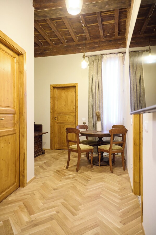 Un área de comedor con una mesa y sillas de madera, una puerta de madera y un suelo con estampado en espiga.
