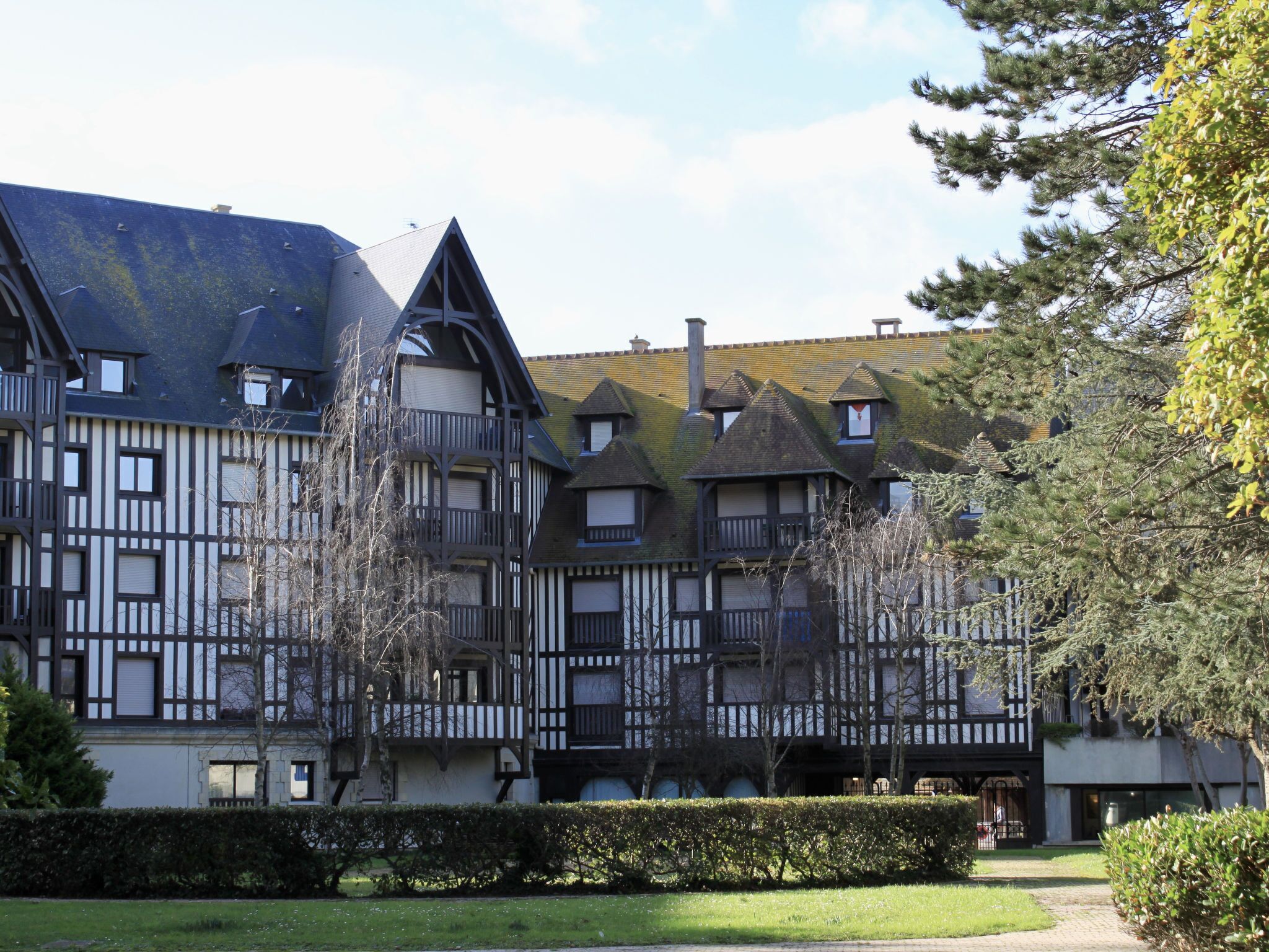 A traditional European-style building with multiple balconies and a garden area in front.