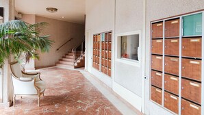 Un corridoio con pavimento in marmo, una scala, una pianta e una fila di armadietti in legno.