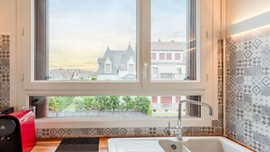 Une cuisine avec deux grandes fenêtres, un évier et une machine à café.
