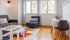 Un salon moderne avec un canapé, une petite table, un fauteuil et un tapis coloré.