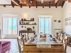 Un espace repas avec une table en bois, des chaises et une vue dégagée grâce à de grandes fenêtres.