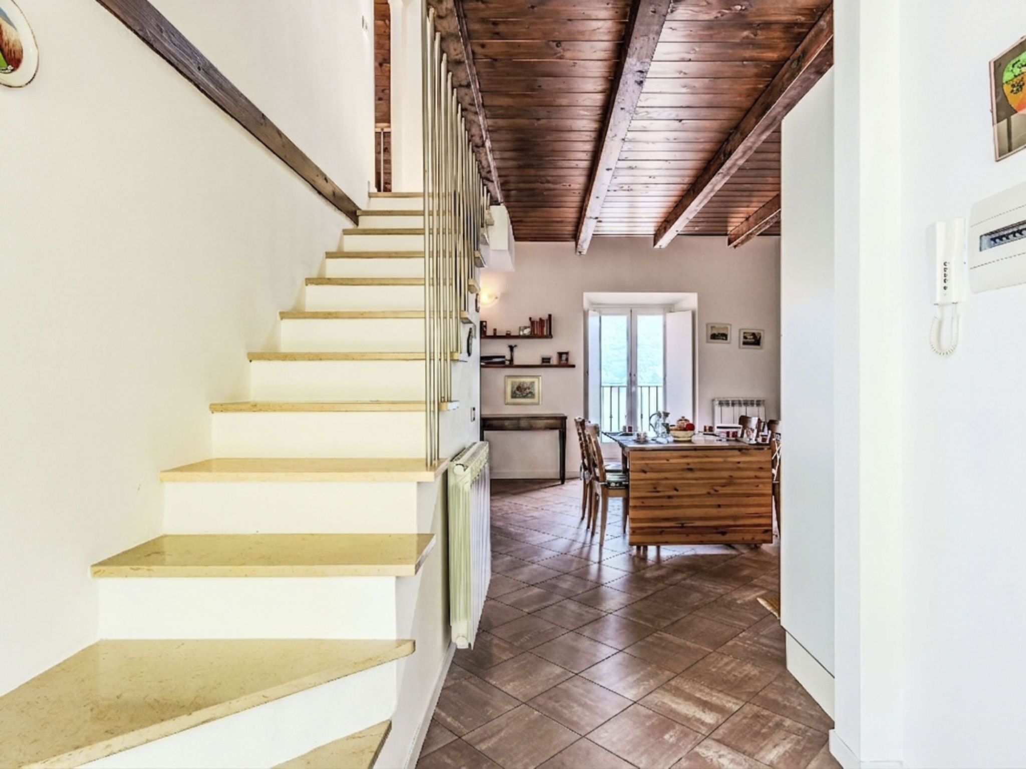 A staircase leading to a dining area with a wooden table and chairs.