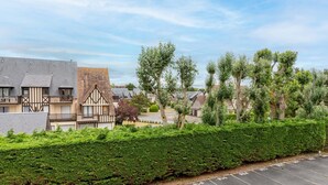 A parking lot with numbered spaces, adjacent to a row of traditional half-timbered houses with visible windows and balconies. - Cabourg Plage by Interhome (Cabourg)
