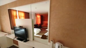 A hotel room with a large mirror, a television on a desk, a coffee maker, and a brown chair. - Arena Hotel Shirvan (Shirvan)
