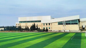 A modern building with a flat roof and large windows, surrounded by a green field. - Arena Hotel Shirvan (Shirvan)