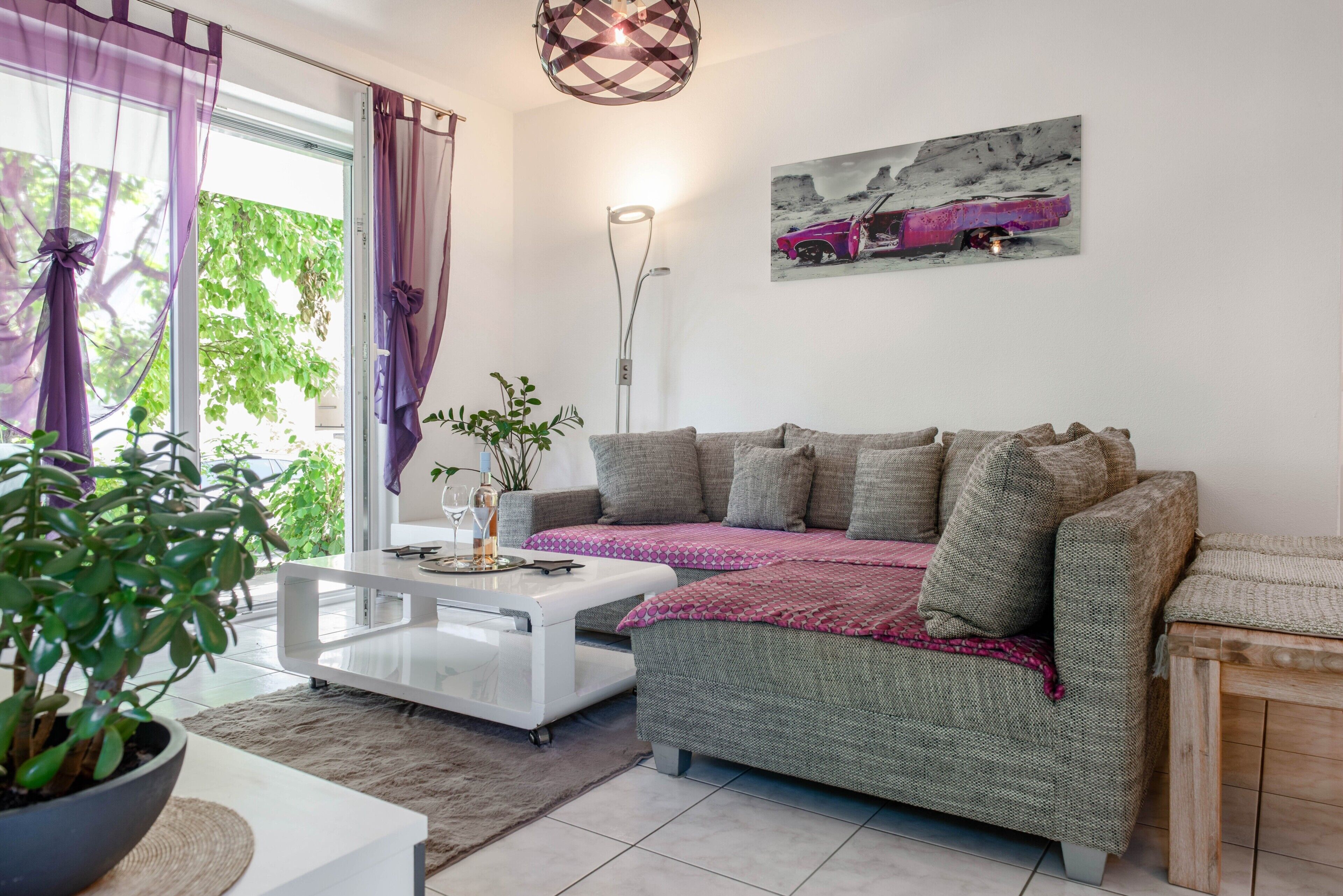 Een woonkamer met een bank, een salontafel, een vloerlamp en een schilderij aan de muur.