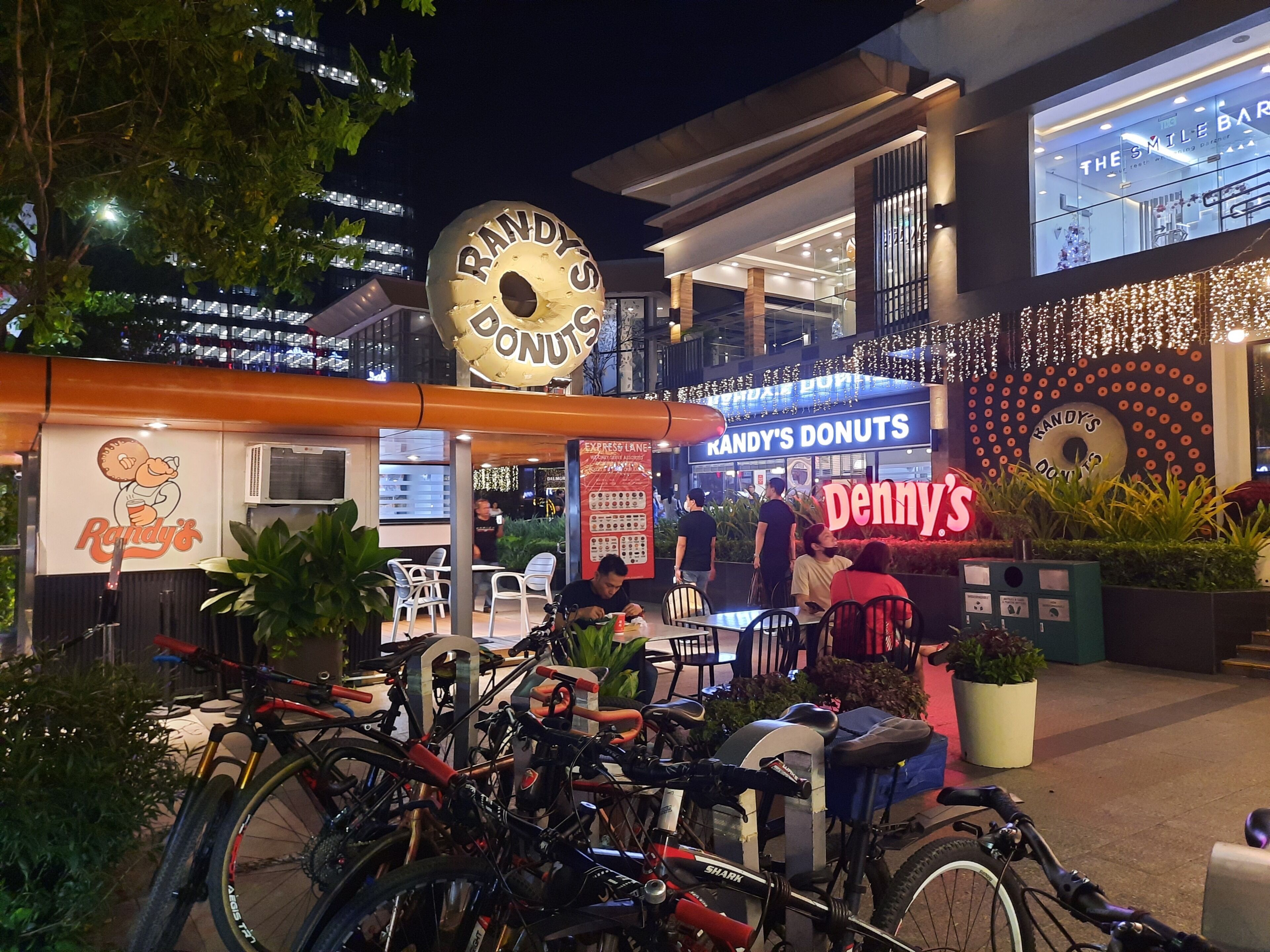 Une boutique de beignets appelée Randy's Donuts, avec une terrasse et un espace de stationnement pour vélos.