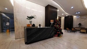 A reception desk with a dark marble top, a potted plant, and a Christmas tree with gifts.