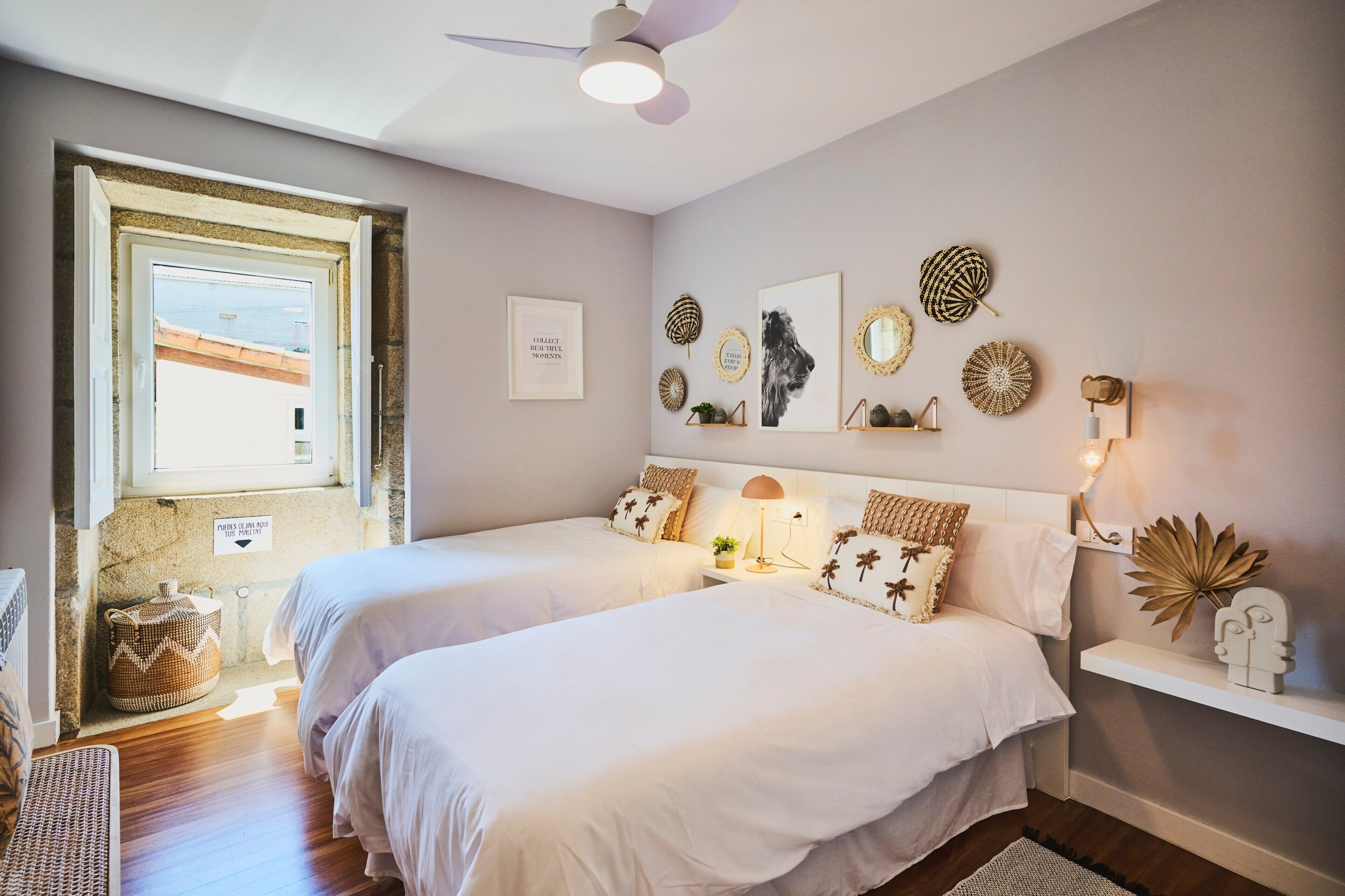 Una camera da letto con due letti, una ventola a soffitto, decorazioni alle pareti e una finestra con vista.