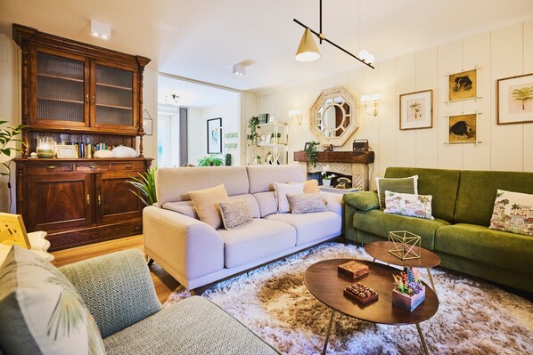A living room with a beige sofa, a green sofa, a wooden cabinet, and a coffee table with decorative items.