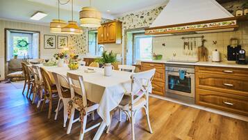A kitchen with wooden cabinets, a dining table with chairs, and a coffee machine.