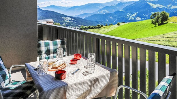 A balcony with a table set for dining, overlooking a mountainous landscape. - La Siala Apt.66 by Interhome (Falera)