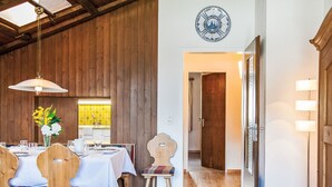 A dining area with wooden walls, a white table set with plates, glasses, and a vase of flowers. - La Siala Apt.66 by Interhome (Falera)