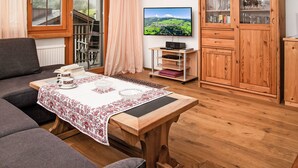 A cozy living room with a sofa, a wooden coffee table, a TV, and a cabinet with glass doors. - La Siala Apt.35 by Interhome (Falera)