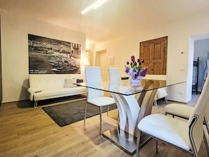 A modern living room with a glass dining table, white sofas, and a large black-and-white photograph on the wall. - La Scaletta by Interhome (Dongo)