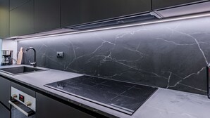 A modern kitchen with a black countertop, a Bosch induction cooktop, a black faucet, and a marble backsplash. - La Scaletta by Interhome (Dongo)
