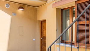 A hallway with a wooden door, a metal railing, and a stone floor. - La Scaletta by Interhome (Dongo)