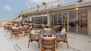 An outdoor seating area with tables and chairs, a staircase, and large windows. - Hotel Royal Bagh - Opposite City Park (Jaipur)
