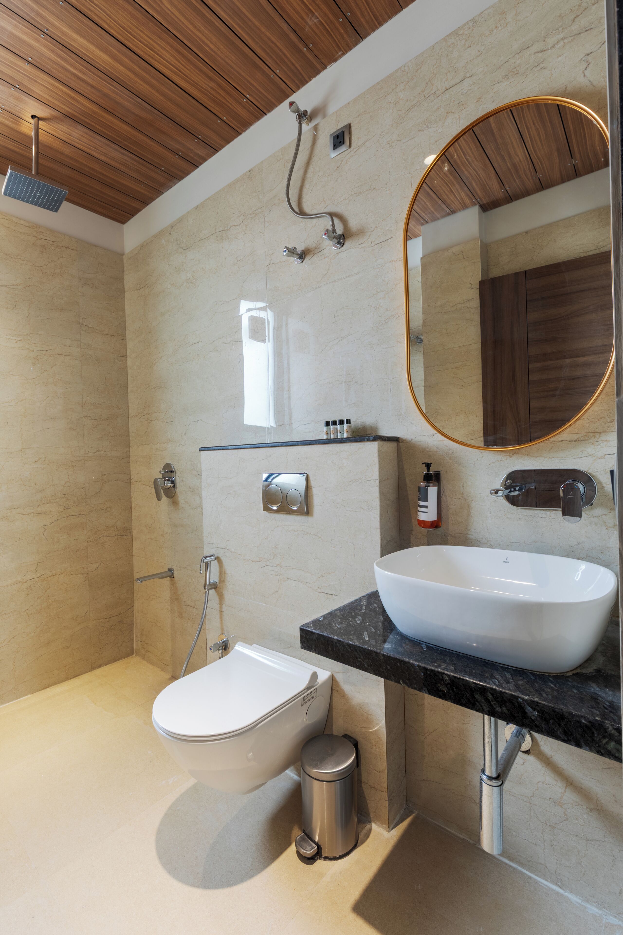 Une salle de bain moderne avec un plafond en bois, un grand miroir ovale, un lavabo blanc et des toilettes.